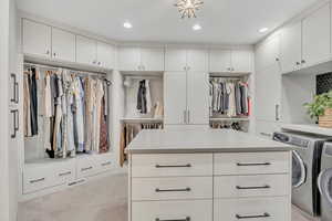 Walk in closet with washer and clothes dryer and light carpet