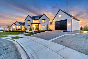 Modern farmhouse with driveway, an outbuilding, stucco siding, and a front lawn