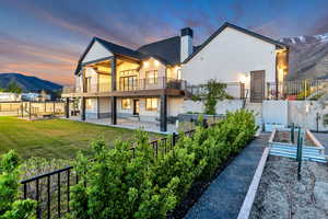 Back of property at dusk featuring a mountain view, a patio, a fenced backyard, and a chimney