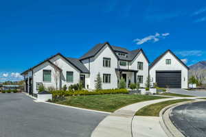 Modern farmhouse style home featuring a front lawn, a garage, and brick siding