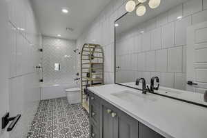 Bathroom with vanity, tile walls, tub / shower combination, recessed lighting, and light tile patterned flooring