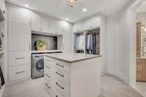 Walk in closet with washer / dryer and light carpet