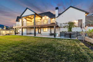 Rear view of property with a patio, a chimney, stucco siding, and a balcony