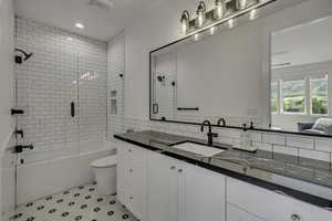 Full bath with vanity, light tile patterned floors, shower / bath combination with glass door, and tile walls