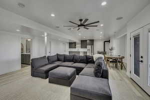 Living room featuring light wood-type flooring, a wood stove, a ceiling fan, and recessed lighting