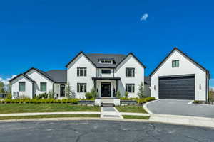 Modern farmhouse with a garage, a front lawn, a porch, brick siding, and asphalt driveway