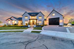 Modern farmhouse style home featuring a yard, driveway, stucco siding, and a garage