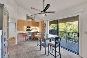 Dining space featuring light carpet, vaulted ceiling, and a ceiling fan