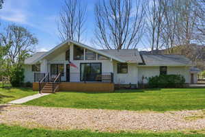View of front of home featuring board and batten siding, a front lawn, roof with shingles, and a wooden deck