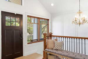 Foyer featuring lofted ceiling, a decorative wall, light wood-style flooring, and hanging lights