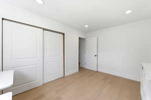 Unfurnished bedroom featuring light wood finished floors, a closet, and recessed lighting