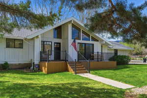 View of front facade with board and batten siding, a front lawn, and roof with shingles