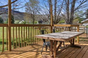 Deck with outdoor dining space, a mountain view, and a lawn