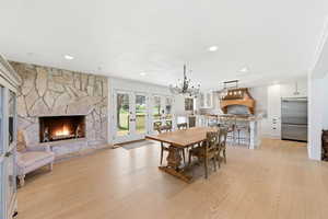 Dining room with a stone fireplace, light wood-type flooring, french doors, and recessed lighting