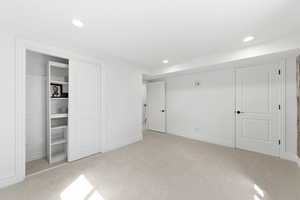 Unfurnished bedroom with light carpet and recessed lighting