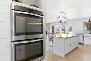 Kitchen with stainless steel appliances, white cabinets, a breakfast bar area, a center island, and light wood-type flooring