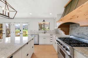 Kitchen with stainless steel appliances, light stone countertops, white cabinetry, light wood-type flooring, and recessed lighting