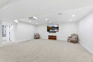 Sitting room with light colored carpet and recessed lighting