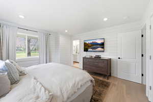Bedroom featuring light wood-type flooring, wooden walls, recessed lighting, and ensuite bath