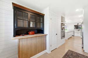 Kitchen with light wood-style flooring, stainless steel appliances, recessed lighting, glass fronted cabinets, and white cabinetry