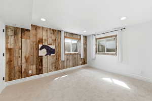 Unfurnished room with carpet floors, wood walls, and recessed lighting