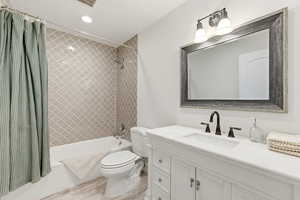 Bathroom featuring vanity, shower / bathtub combination with curtain, and recessed lighting