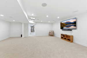 Finished basement with light carpet and recessed lighting