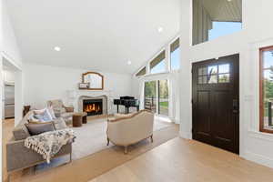 Living room with light wood-style flooring, vaulted ceiling, recessed lighting, and fireplace (capped, not connected) shown with virtual fire for illustration