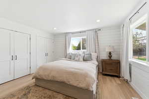 Bedroom featuring wooden walls, two closets, light wood-type flooring, and recessed lighting