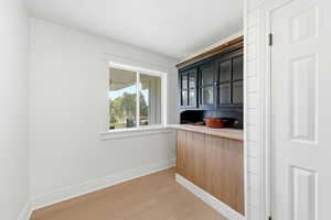 Bar with light wood-style floors and glass fronted cabinets