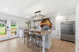 Kitchen featuring white cabinets, high end fridge, and a breakfast bar area