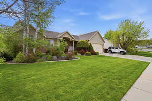 Ranch-style home featuring a front lawn, driveway, a garage, and brick siding
