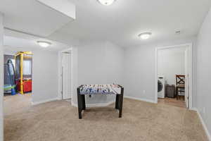 Playroom featuring light carpet, washer / clothes dryer, and a textured ceiling