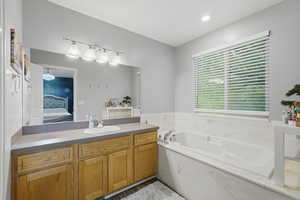 Bathroom featuring vanity, connected bathroom, and a bath