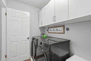 Laundry room with washing machine and clothes dryer, cabinet space, and wood finished floors