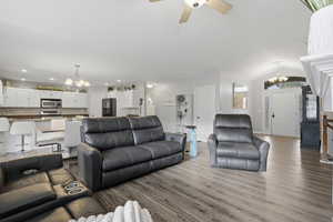 Living room with a chandelier, wood finished floors, a ceiling fan, and vaulted ceiling