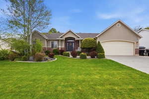 View of front facade with brick siding, a garage, driveway, and a front yard