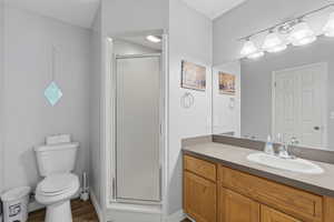 Full bath with a stall shower, vanity, and dark wood-style floors