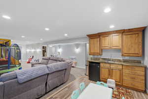 Kitchen with open floor plan, wood finish cabinets, dark stone countertops, light wood finished floors, and recessed lighting