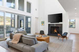 Living room featuring light wood-style floors, a fireplace, a high ceiling, and recessed lighting