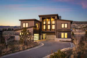Contemporary home with driveway, stone siding, a mountain view, and an attached garage