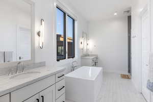 Bathroom featuring two vanities, a freestanding bath, a stall shower, and recessed lighting