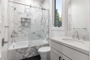 Full bath featuring vanity and bath / shower combo with glass door