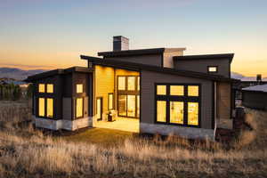 Back of property with stone siding, a chimney, a patio area, and a mountain view
