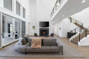 Living area with a brick fireplace, a high ceiling, wood finished floors, and recessed lighting