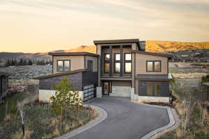 Modern home featuring stone siding, a mountain view, and asphalt driveway