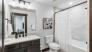 Bathroom featuring vanity, shower / tub combo with curtain, and recessed lighting