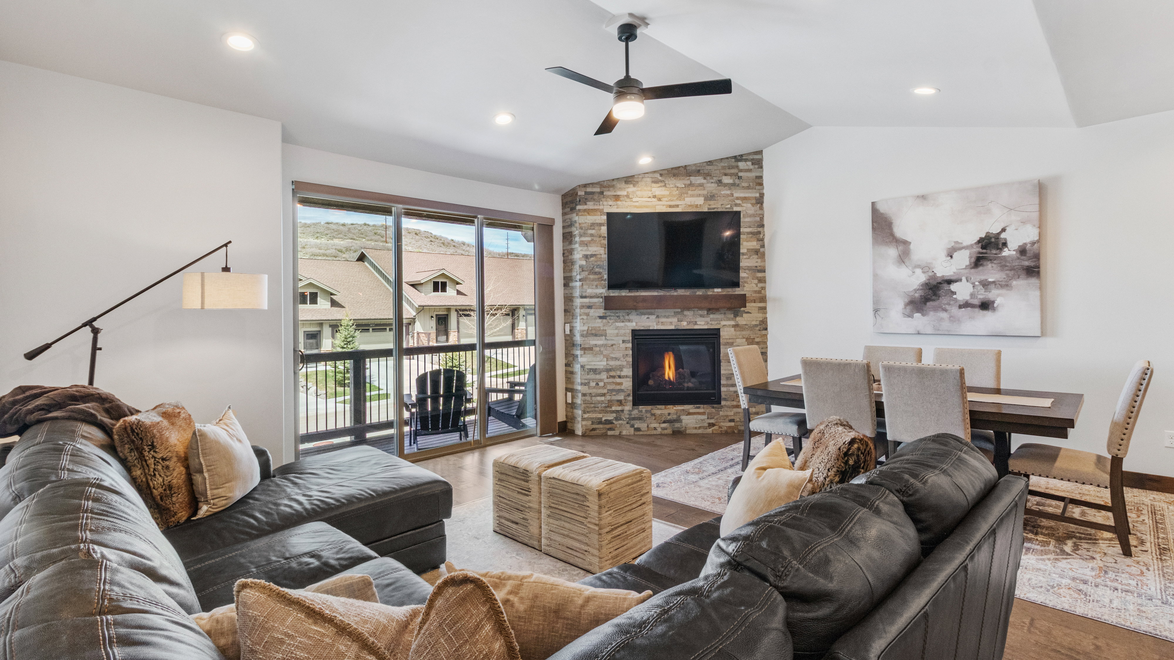 Living area with wood finished floors, a ceiling fan, a stone fireplace, vaulted ceiling, and recessed lighting