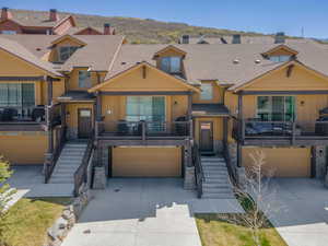 View of front of house with stone siding, a garage, driveway, and a shingled roof