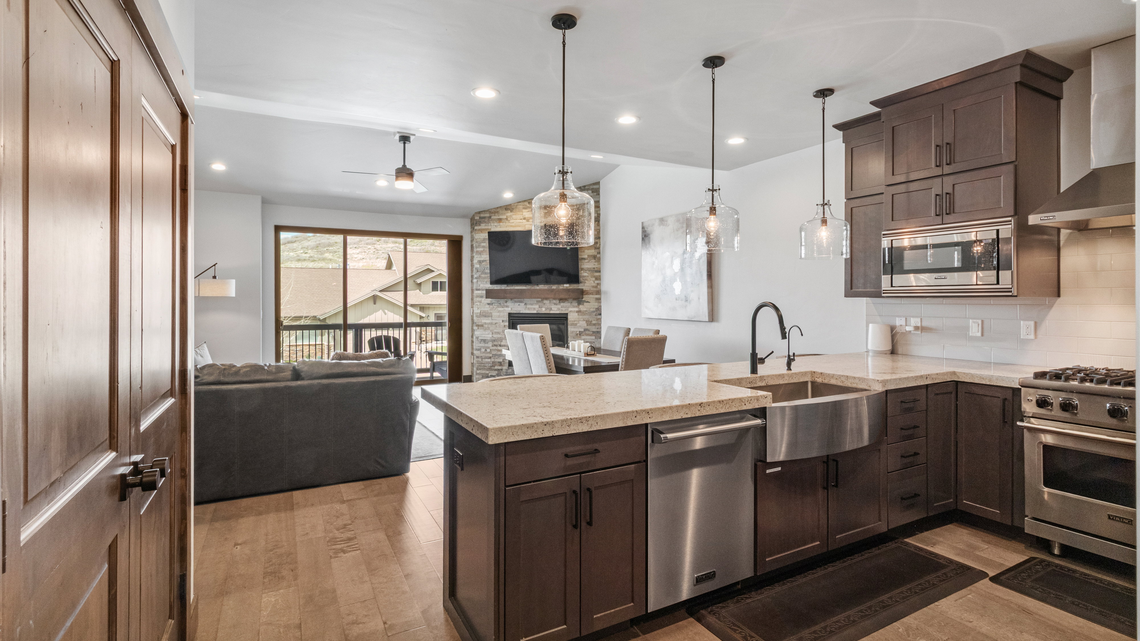 Kitchen with a fireplace, a peninsula, stainless steel appliances, dark wood finish cabinets, and light wood-type flooring